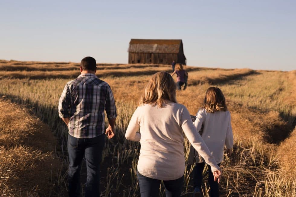 A family walking together through a field at sunset