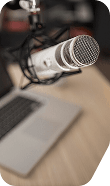 A podcast microphone beside a laptop
