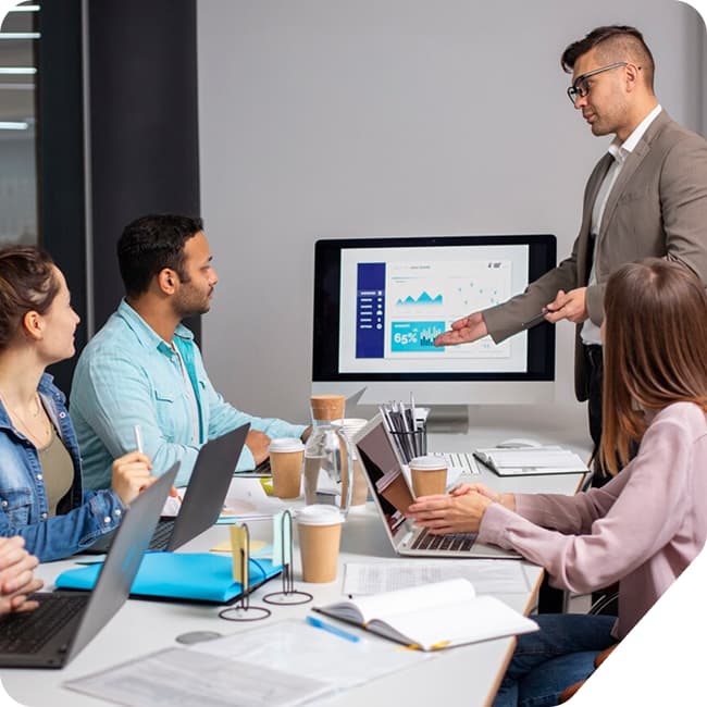 A leader presenting performance data to a team around a laptop